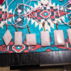 A group shot of faceted rose quartz pendants with wire wrapped bails on a southwest style decorative placemat.