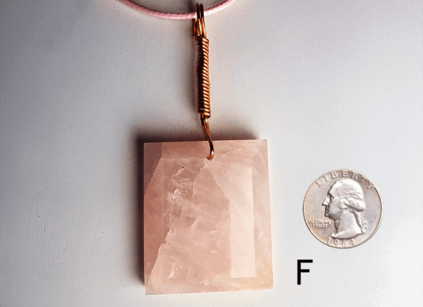A pink rose quartz faceted pendant with a copper wire wrapped bail, and a quarter for size comparison. Labeled F.