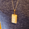 A pink rose quartz faceted pendant with a copper wire wrapped bail being worn.