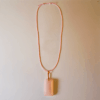A pink rose quartz faceted pendant with a copper wire wrapped bail, with full display of an adjustable pink wax cord necklace attached.