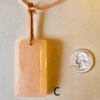 A pink rose quartz faceted pendant with a copper wire wrapped bail, and a quarter for size comparison. Labeled C.