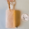 A pink rose quartz faceted pendant with a copper wire wrapped bail, and a quarter for size comparison. Labeled E.