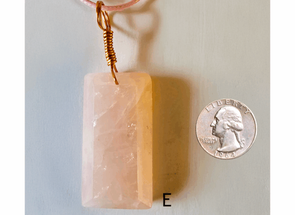 A pink rose quartz faceted pendant with a copper wire wrapped bail, and a quarter for size comparison. Labeled E.