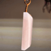 A pink rose quartz faceted pendant with a copper wire wrapped bail.